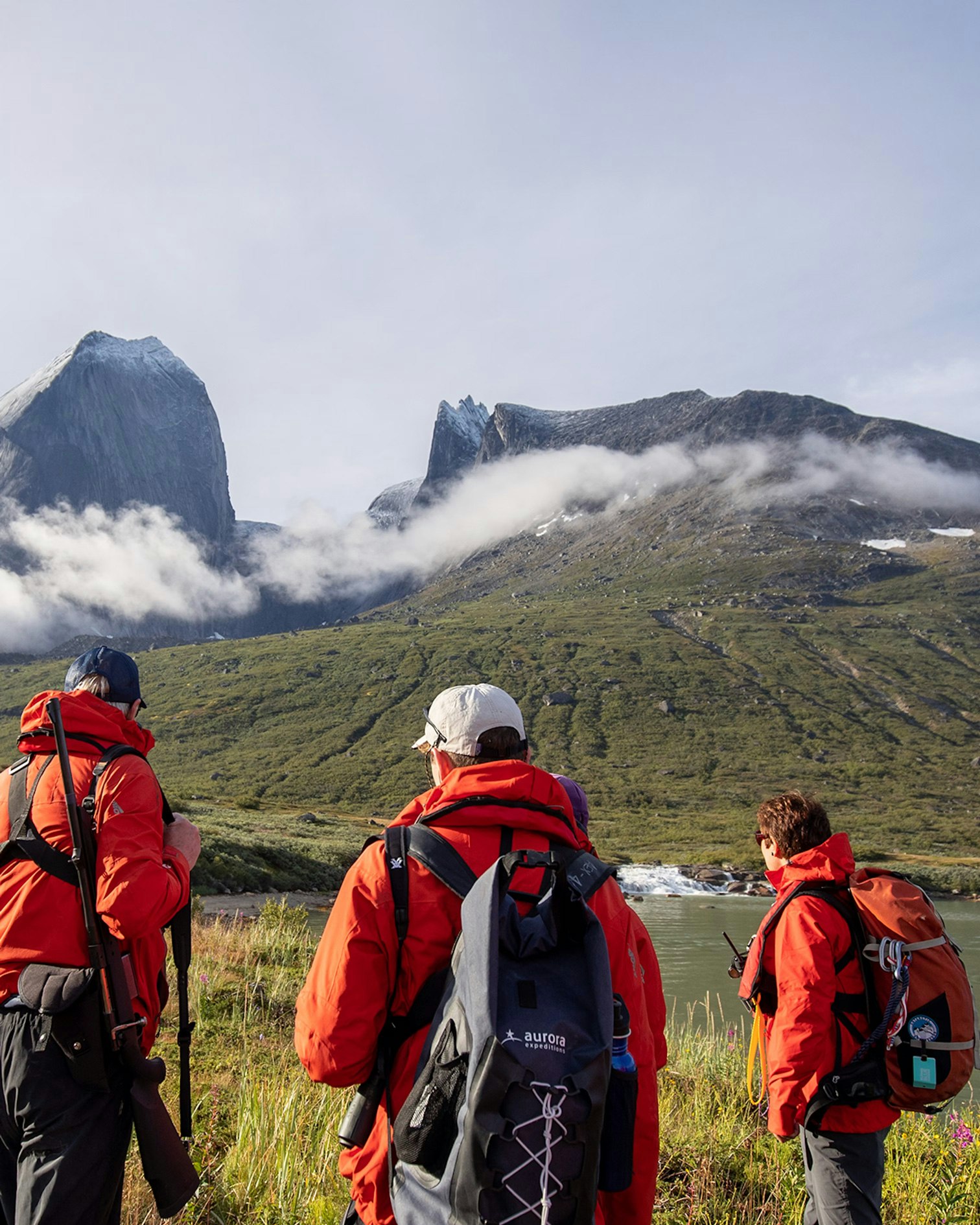 3 expedition team members hiking up a cloud covered mountain
