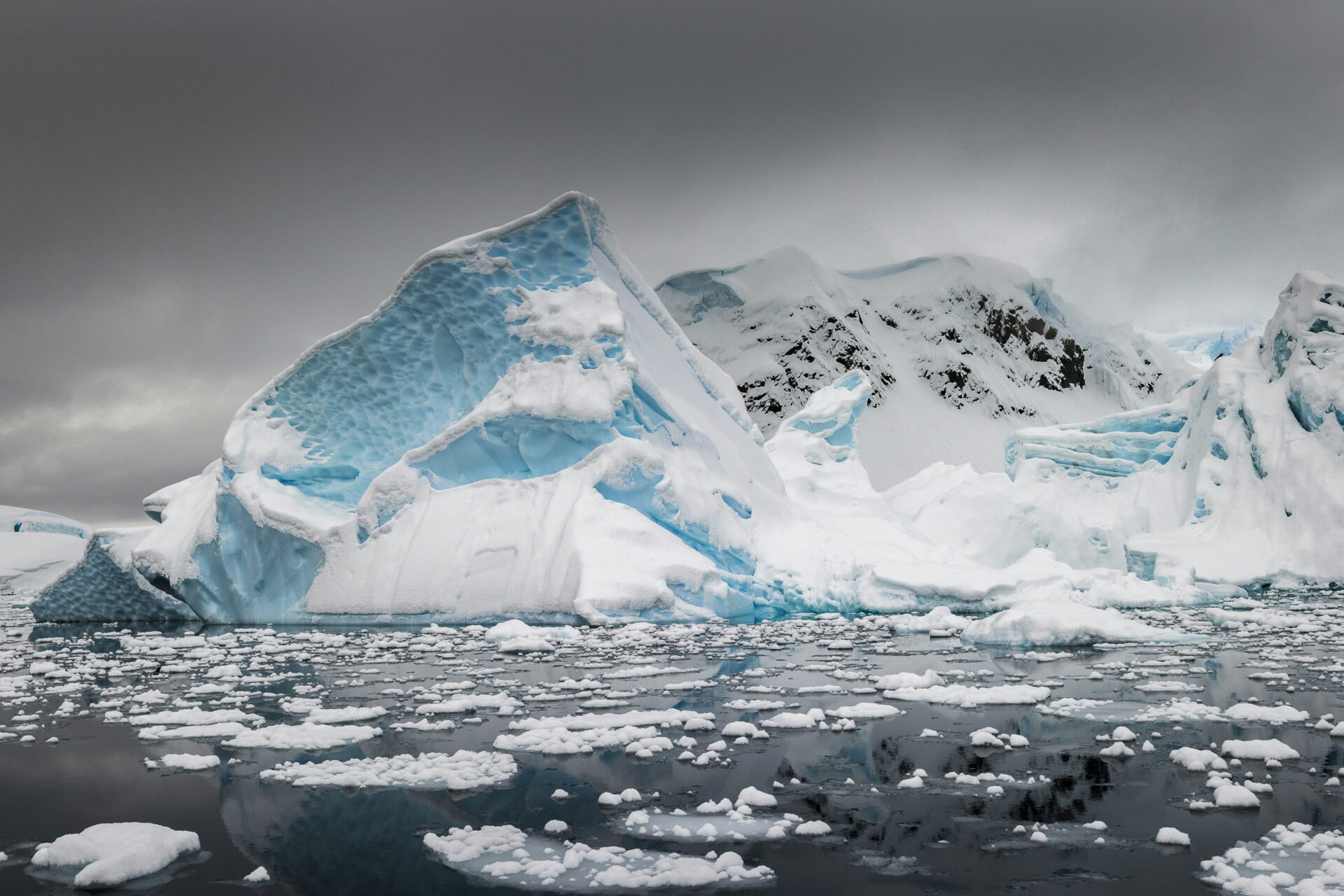 Iceberg-rising-above-a-sea-of-nylas-ice-and-small-ice-floes-covered-in-fresh-snow-Paradise-Harbour-A
