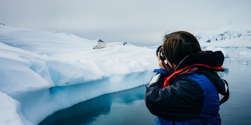Photographer taking a photo of a seal on an iceberg
